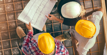 Three men in construction hats reviewing blue blue prints